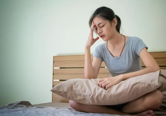 Pregnant mom sitting on her bed and feeling nauseous 